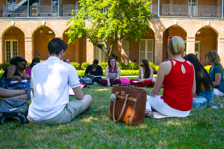 a class sitting in a circle in Woods Quad